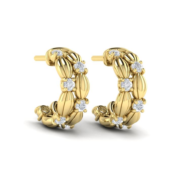 Angled view of Vlora Madeleine yellow gold hoop earrings with sculpted scallop-shell details and two rows of diamonds.