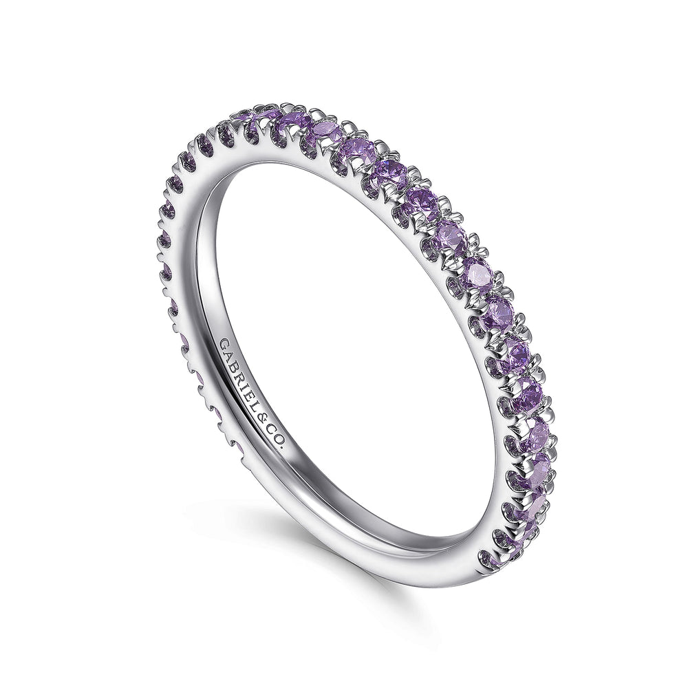 An angled view of a white gold ring against a white background. The ring features amethyst gemstones set in place by small prongs in gleaming white gold.
