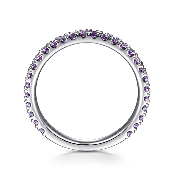 A side profile view of a white gold ring against a white background. The ring features amethyst gemstones set in place by small prongs in gleaming white gold.