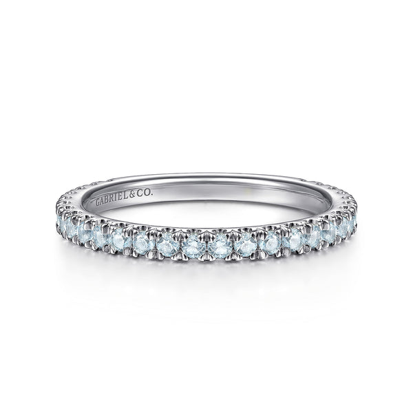 A front view of a white gold wedding band against a white background. The ring features sky blue topaz gemstones set in place by small prongs in gleaming white gold.