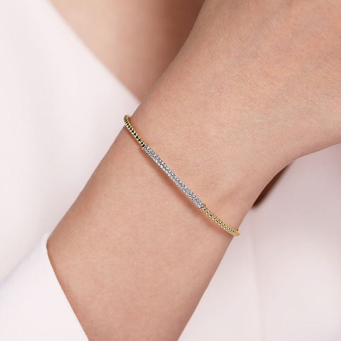 Gabriel & Co Bujukan diamond bar split bangle worn on the wrist, showing its slim yellow gold beaded design.