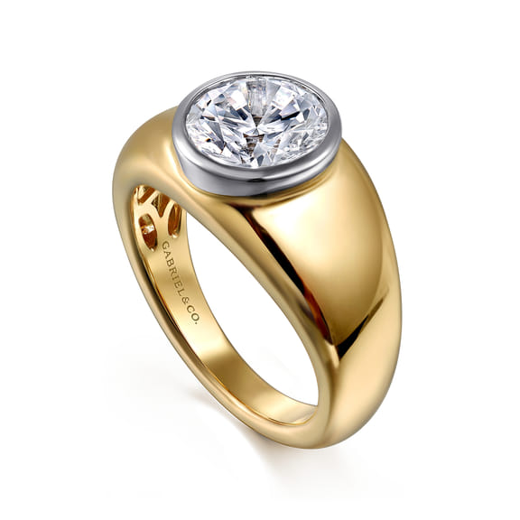 Angled view of a two-tone gold engagement ring showing the round diamond, white gold bezel and sculpted yellow gold band.