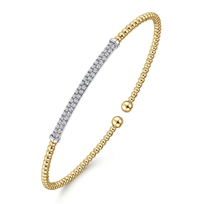 Angled view of the Gabriel & Co Bujukan bangle showing the diamond bar, yellow gold beads and open split design.